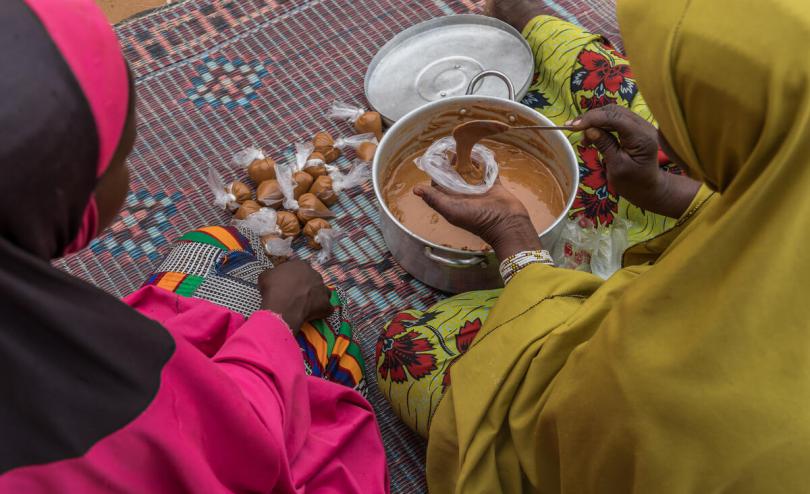 Teenage girl prepares food with her mother outside their home in Tillaberi region, Niger