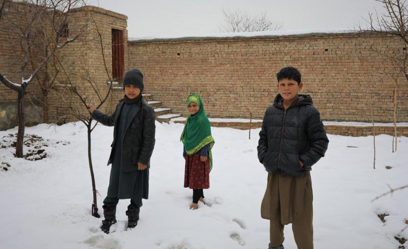 Siblings Abrisham*, 11, Wazhma*, 9 and Omar*, 13 outside their home in the outskirts of Kabul, Afghanistan