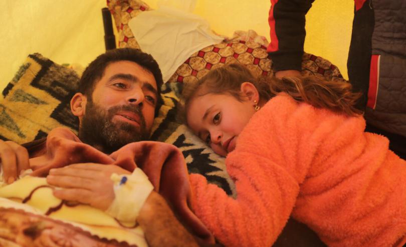 Dina*, 6, hugs her father Lutfi* who is recovering from his injuries [Khalil Ashawi/Save the Children]