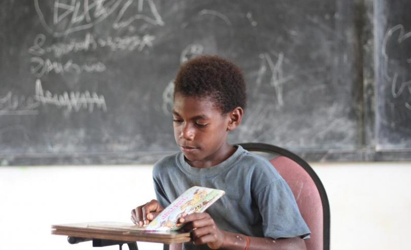 Roseh (10) is reading books at an evacuation centre in Vanuatu. Photo by: Elisa Mondou/Save the Children Vanuatu