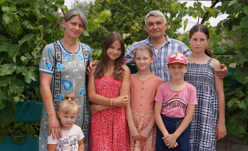 Stanislav*, 57, with his wife Oksana*, Anastasiia*(3), Mariia*(14), Victoria*(9), Larisa*(9), and Olga*(14) [left to right] pose for a family portrait in the garden near their house in Southern Dnipro, Ukraine