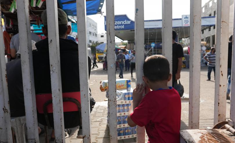 a child standing behind a fence in Gaza