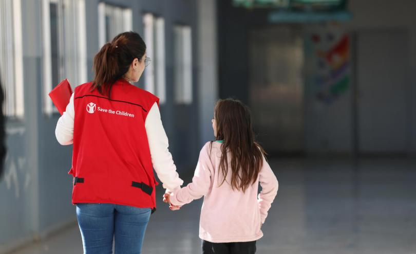 Save the Children staff with a girl in a school used as a shelter