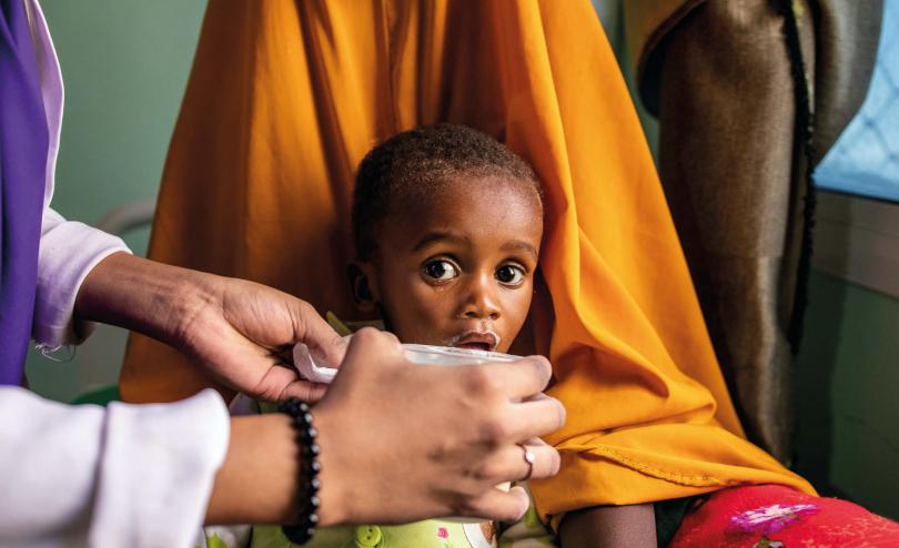 Nala* (20) holds her son Ahmed* (1) while Muna (23) gives him therapeutic milk at a Save the Children-supported stabilisation centre in Somalia