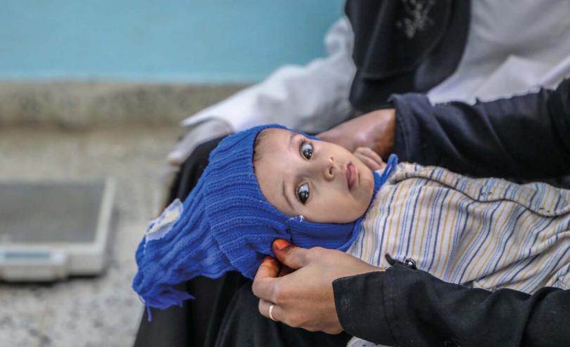 Suha*, 8 months old, held by her mother, in a health facility supported by Save the Children in Taiz governorate, Yemen 