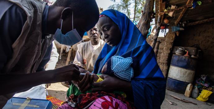 Healthworker Nura Ibrahim administers a vaccine to 22-day-old Rukayya outside his home in Jigawa State, Nigeria.