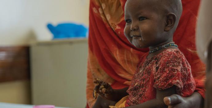 Saadia, 20, feeding food paste to her daughter Aisha