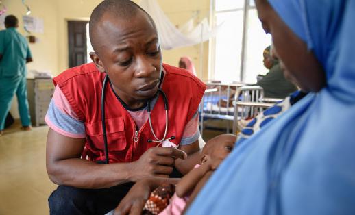 Doctor Aluh Francis helping a mother breastfeed in a stabilisation centre in Nigeria