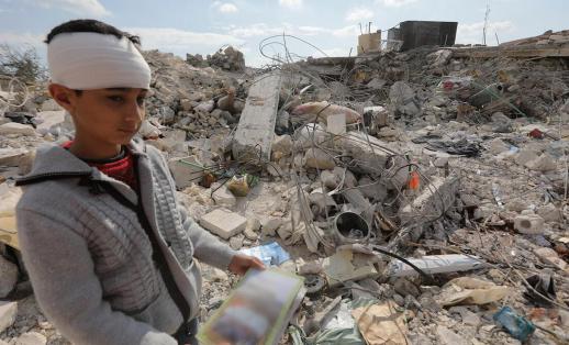 Nawras,13, holds a book he found in the rubble of his home