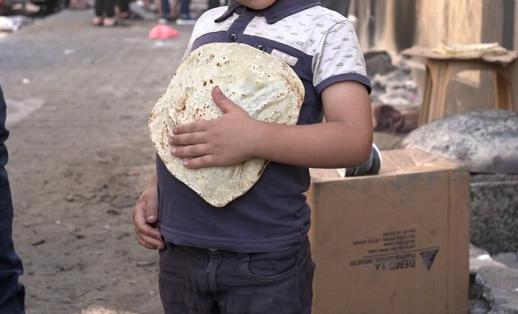 A young boy holds some bread on a street in North Gaza.