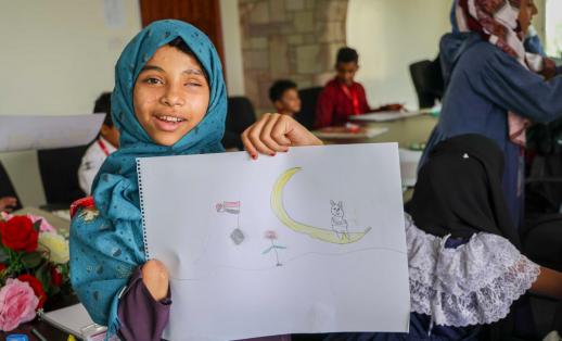 Maha*, 10, from Yemen, holding a drawing that she drew during a workshop for injured children organised by Save the Children