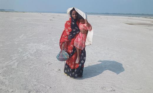 Roksana,34, carrying daughter Rumi, 5, crossing land during a heatwave in Bangladesh