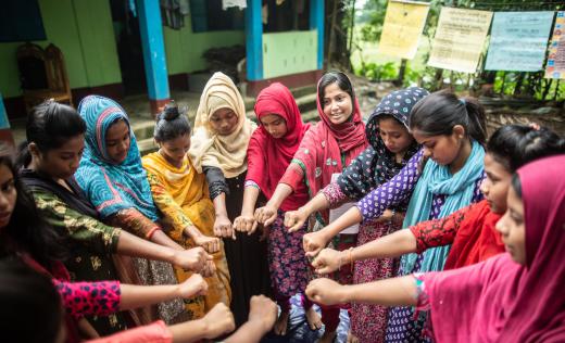 Young women's group standing in a circle putting their hands in the middle, Sylhet, Bangladesh