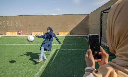 Rama*, 14, takes photos of her sister Hiba*, 17, playing football in Za’atari camp for Syrian refugees, Jordan 