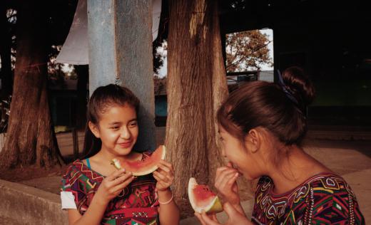 Cousins Anabely, 11, and Maria Elena, 12, eating fruit at school in Quiche district, Guatemala