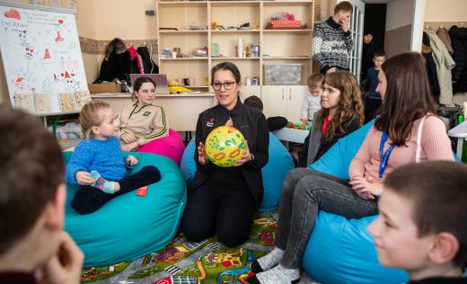 SCI CEO Inger Ashing holds a ball and plays with children in a Child Friendly Space in Kyiv region, Ukraine.