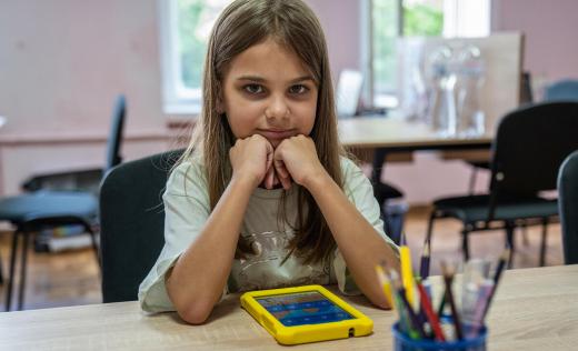 Anna*, 7, poses for portrait as she studies with tablet in Digital Learning Center for teachers in Mykolaiv, Ukraine