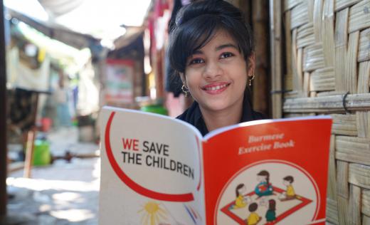 Nuri*, 15, smiles with a Save the Children exercise book near her home in a Rohingya camp in Bangladesh