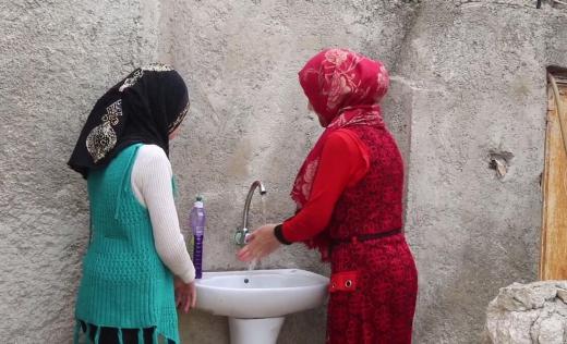 Cousins Zina*, 10, and Nawal*, 14, wash their hands, North West Syria