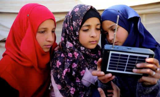 Nour*, 12 listening to the radio with her friends Lina* (left), 11 and Maha* (right), 12