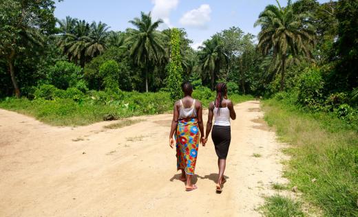 Cousins Kpemeh*, 18 and Kuji*, 19 walk home hand in hand in Kailahun, Sierra Leone