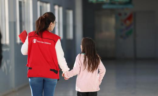 Save the Children staff with a girl in a school used as a shelter