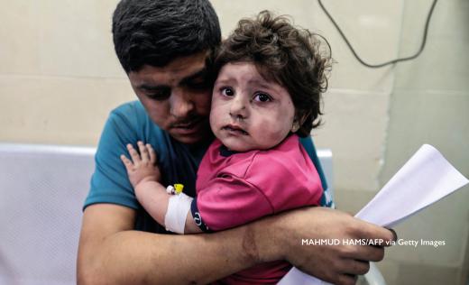 A child in Gaza is held by her father. MAHMUD HAMS/AFP via Getty Images