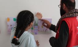Eda*,10, hangs her drawing with Osman from Save the Children