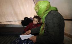 Weam*, 8 and his mother Feryal* in a tent reading a book together