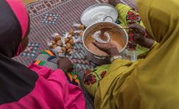 Teenage girl prepares food with her mother outside their home in Tillaberi region, Niger