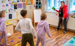 A Save the Children employee throws a ball to (from left to right) Maria*, 7, Symon*, 7 and Larissa*, 7 in the Child Friendly Space