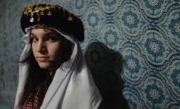 Viyan 15, sits for a portrait wearing traditional Yazidi dress inside her tent, IDP camp, northern Iraq